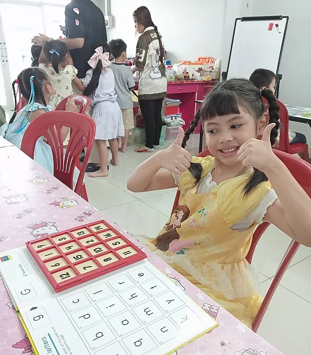 น้องชูนิ้วโป้งดีใจที่ทำแบบฝึกหัดภาษาอังกฤษได้
